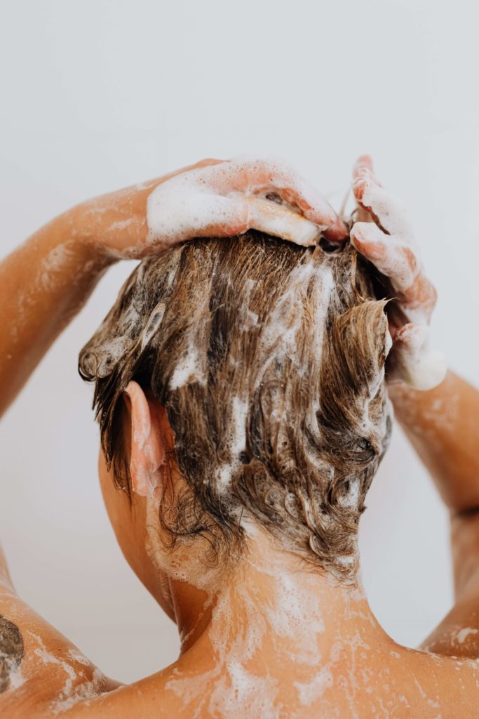 person washing hair with beer shampoo for benefits