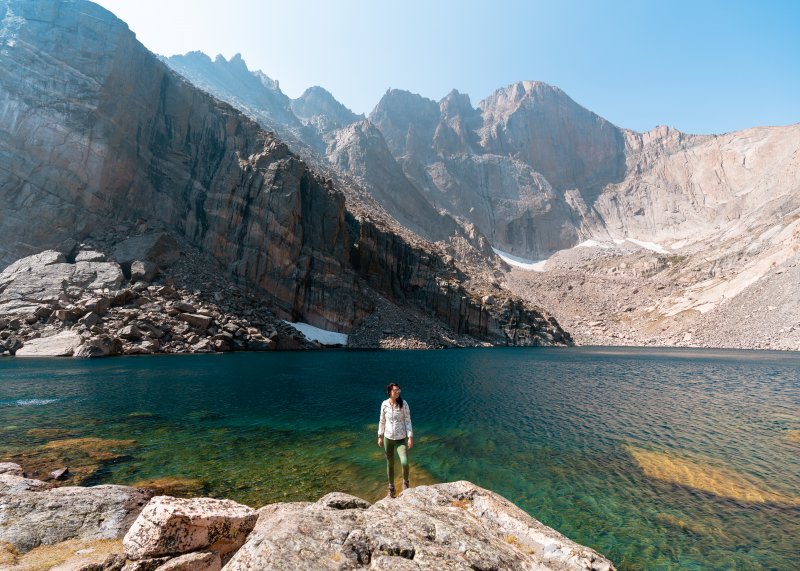 Woman exploring at Rocky Mountain National Park surrounded by water and mountains