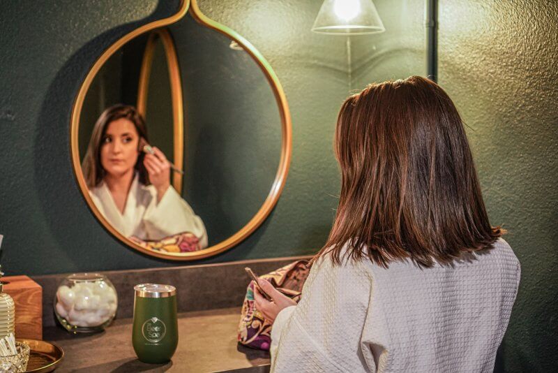 woman looking in mirror putting on makeup at Oakwell Beer Spa in Denver