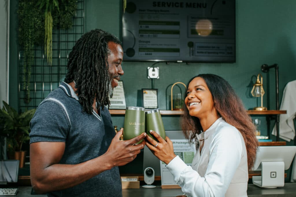 A couple smiles at each other as they make a toast with their Oakwell insulated tumblers