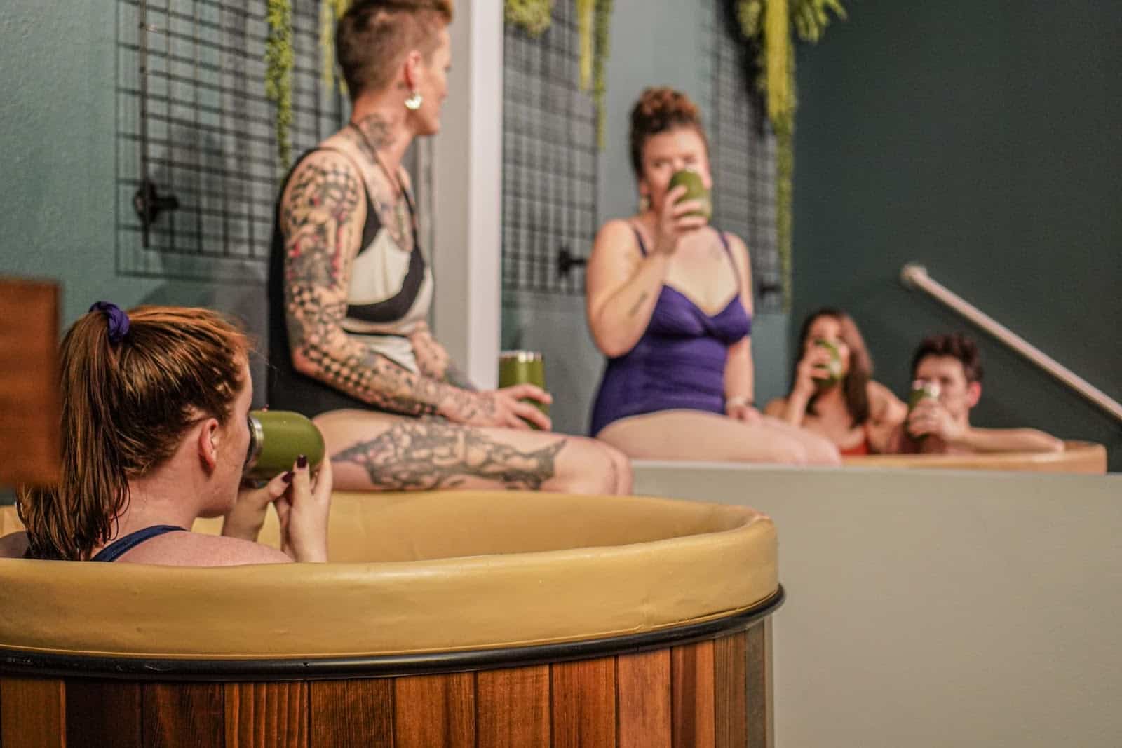 group of five people at Oakwell Beer Spa taking beer baths and drinking from tumblers