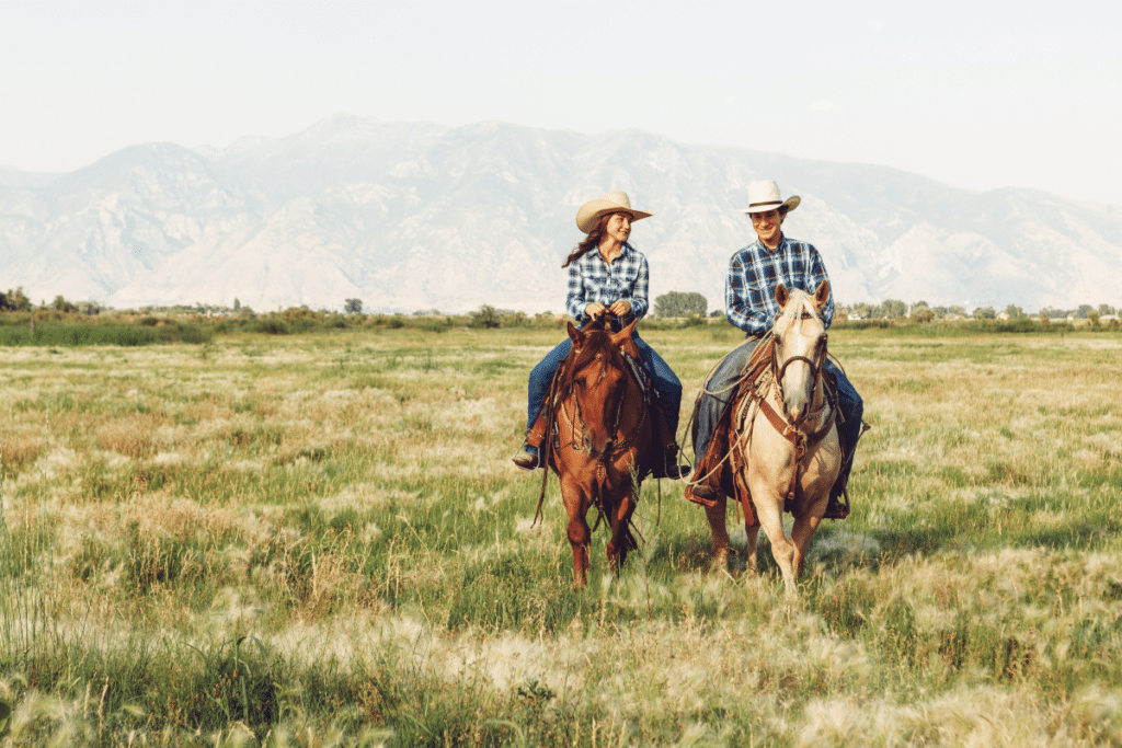 Couple riding horses with mountains in background