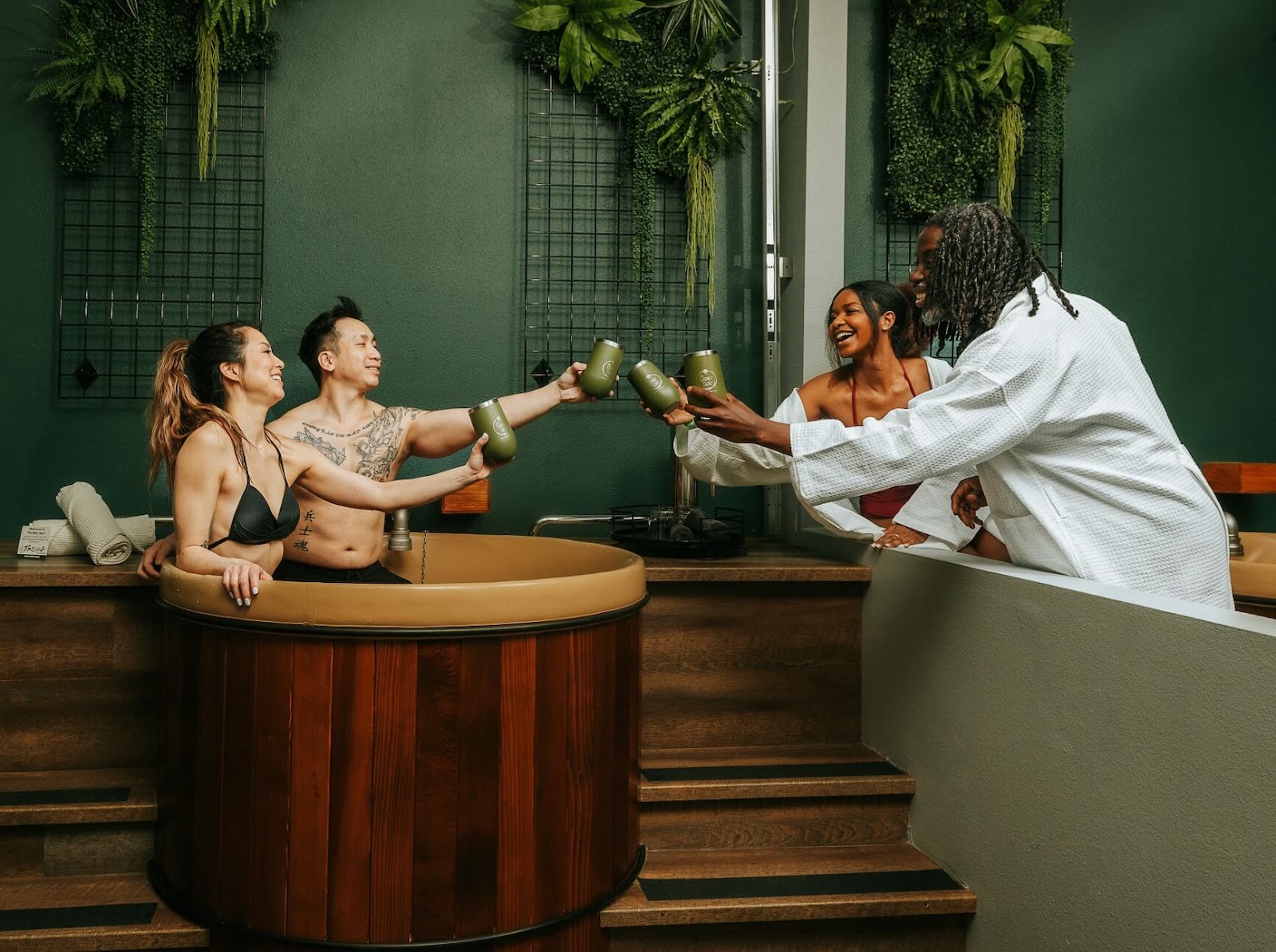 Two couples relaxing at Oakwell Beer Spa in the beer baths with tumblers in hand