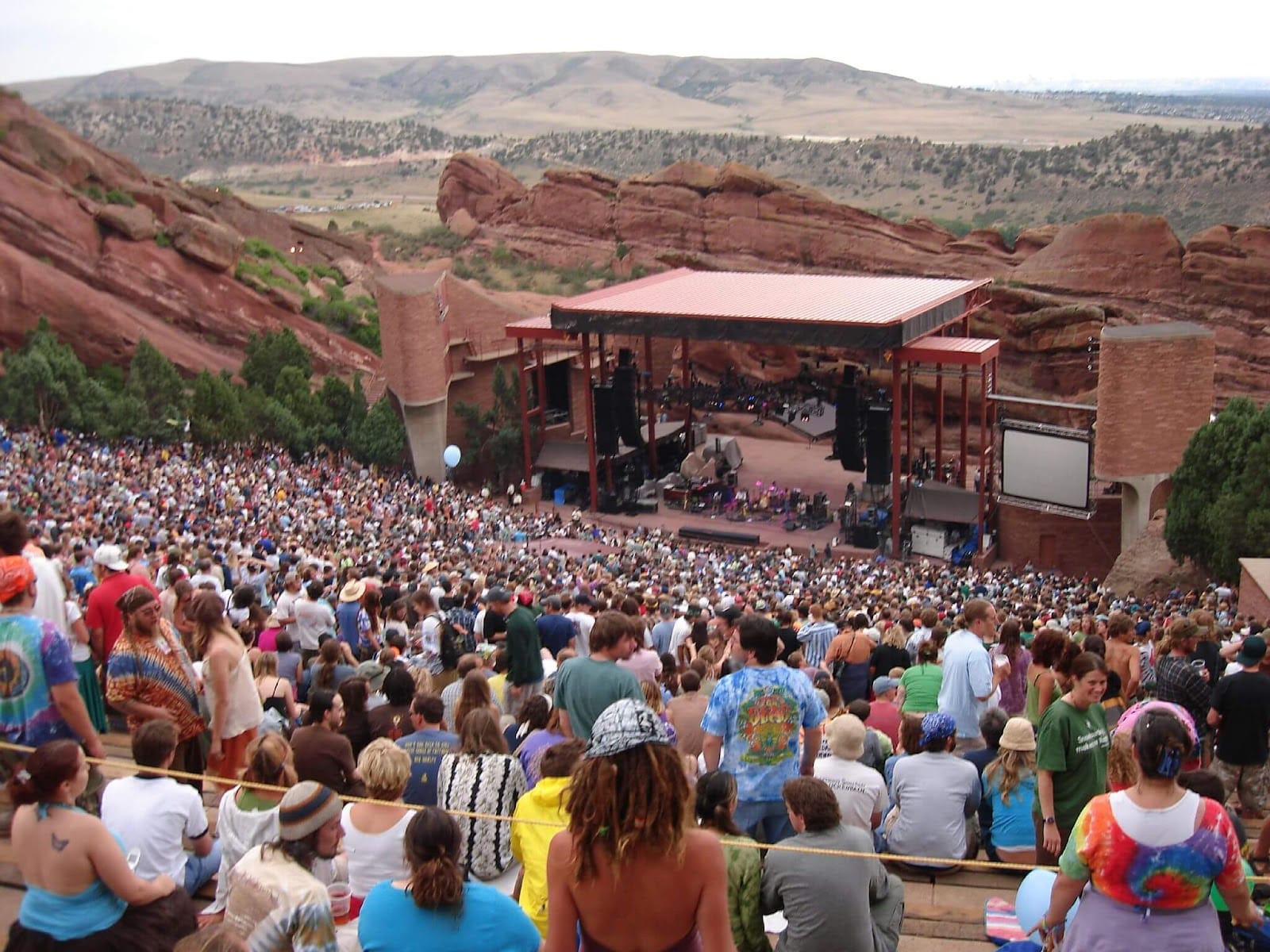 Many people at Red Rocks Amphitheatre for concert surrounded by red rocks and mountain scenery