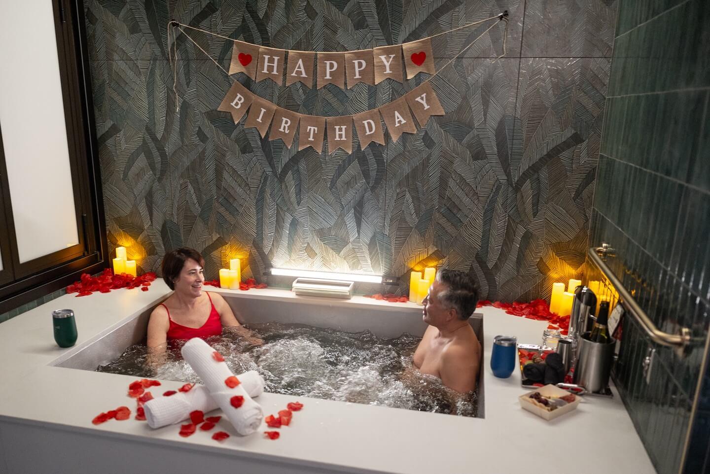 Couple taking a beer bath at Oakwell Beer Spa in Denver with happy birthday banner