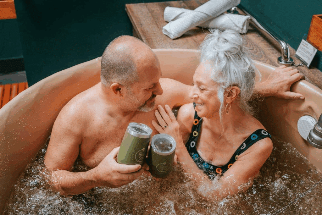 couple smiling at each other while taking a beer bath at Oakwell Beer Spa