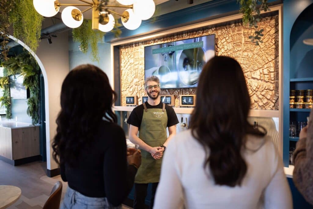 Oakwell Beer Spa employee talking smiling at two guests in the taproom