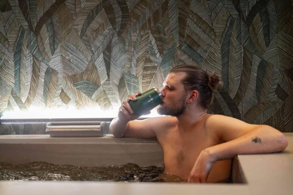 Man drinking from tumbler and taking a beer bath at Oakwell Beer Spa in Denver