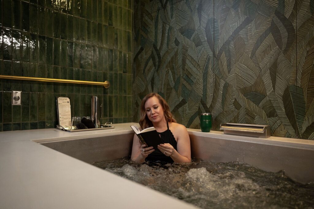 A woman reads her book while soaking at Oakwell
