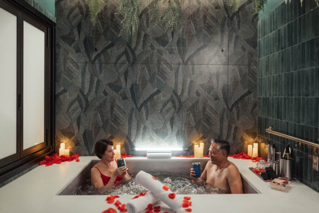 A couple enjoys a romantic beer bath with candles and rose petals