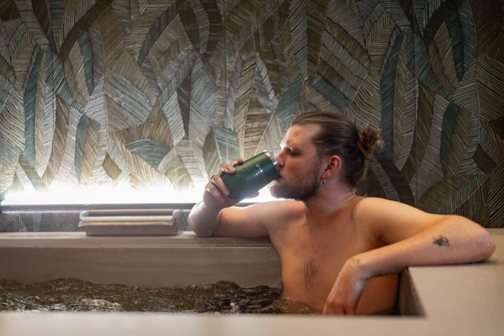 A man enjoys an Oakwell beer-infused soak while enjoying a craft beverage