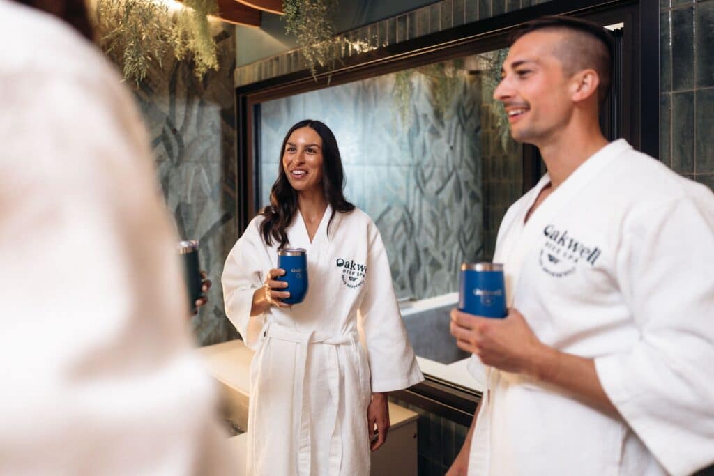 A couple enjoys drinks in their private spa suite while wearing Oakwell robes