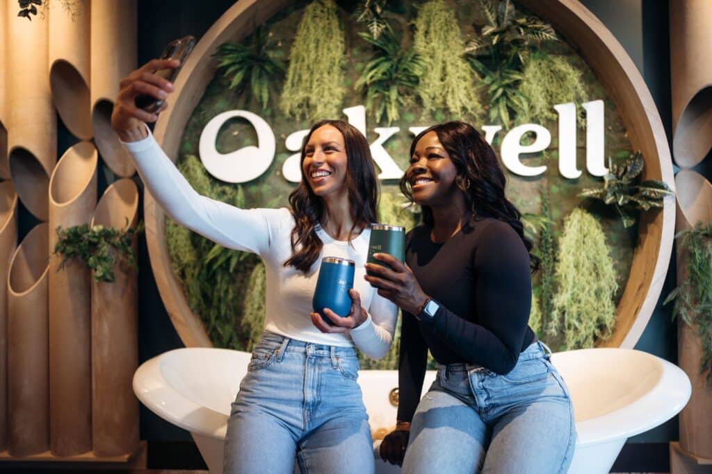 Two women take a selfie in front of the Oakwell sign