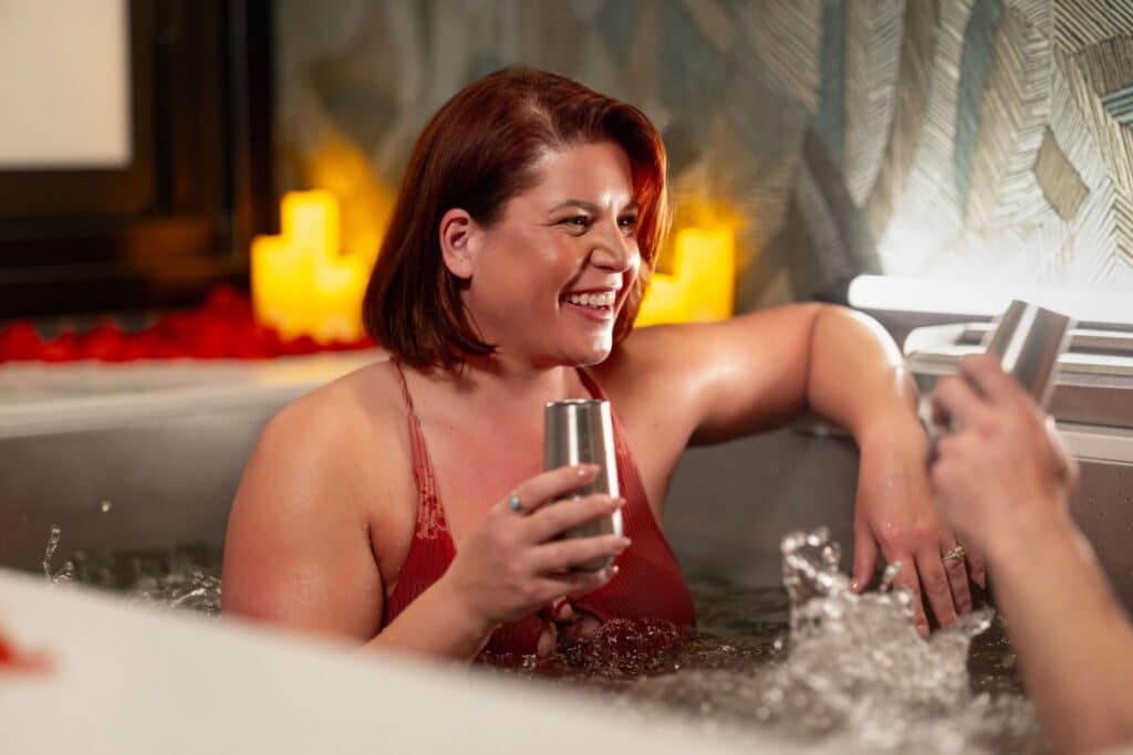 A woman smiles at her partner while enjoying an herbal beer-infused bath