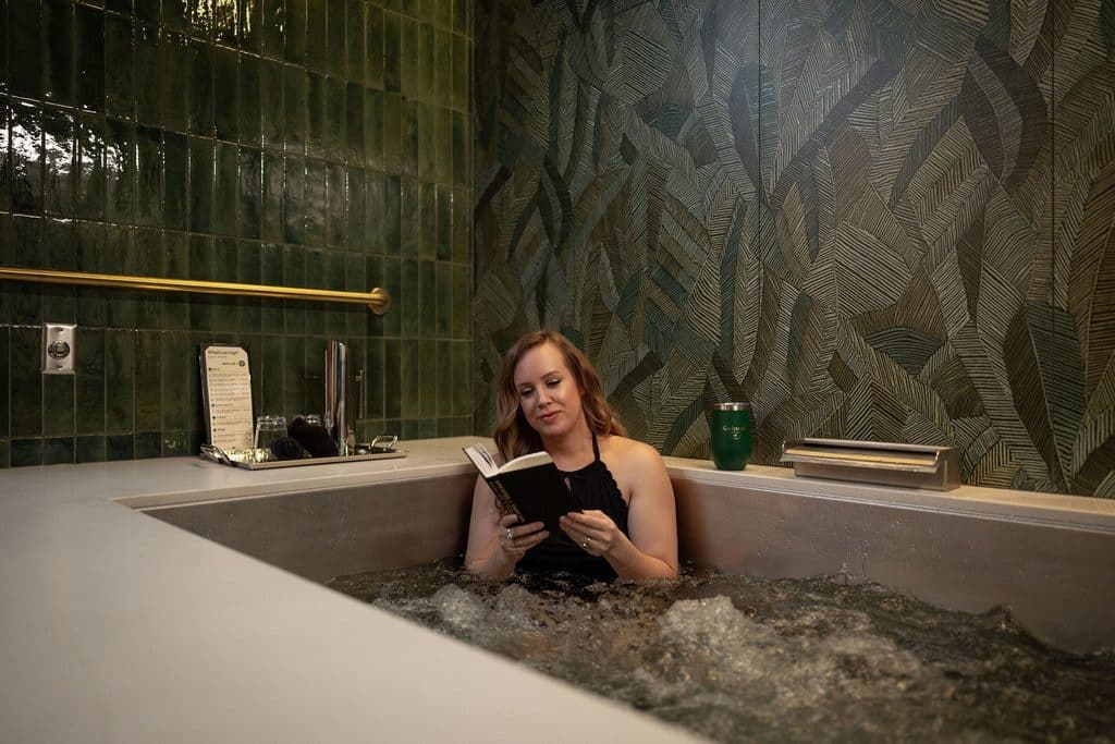 A woman relaxes in a hydrotherapy tub while reading a book